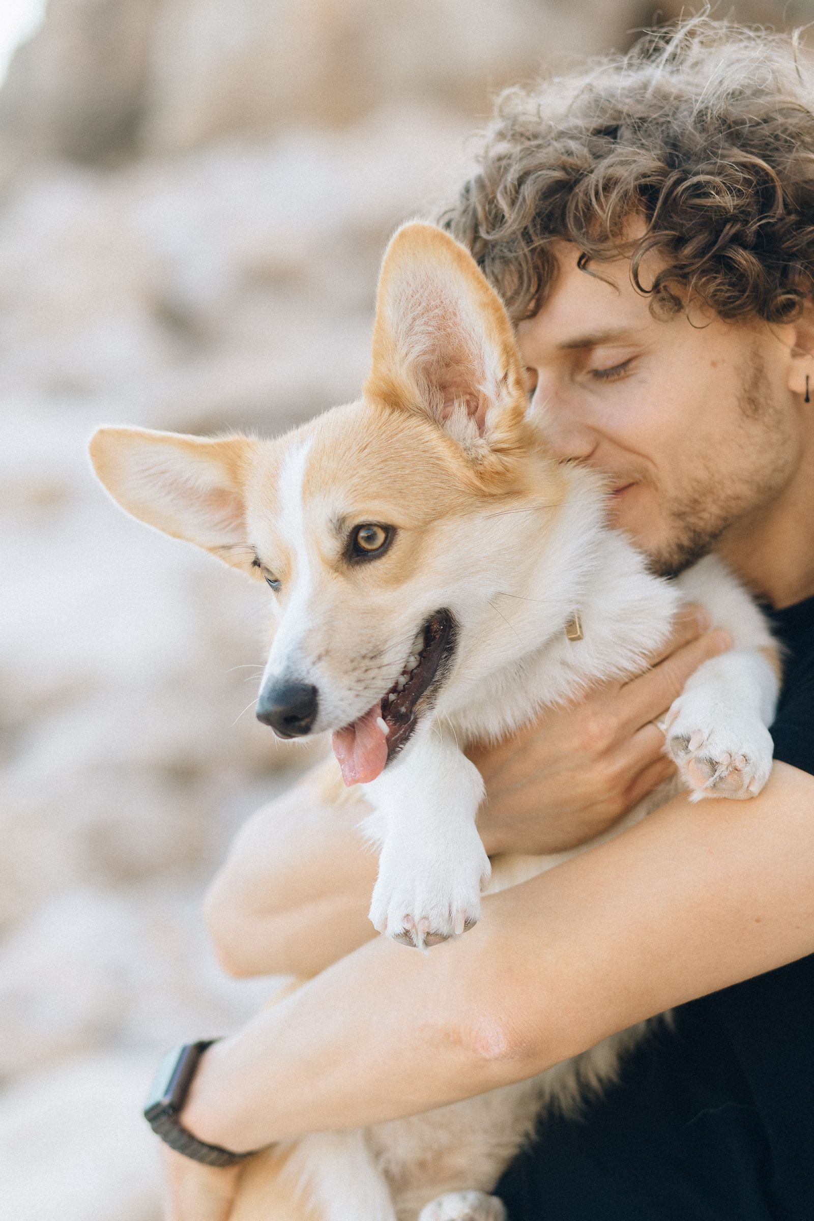 Homem sorrindo carregando seu cachorro no colo, demonstrando o vinculo entre tutor e pet